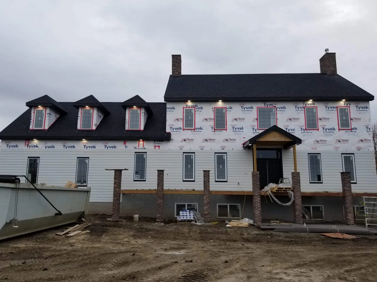 Large custom home under construction with exterior electrical lighting installed